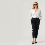 Elegant woman wearing tailored black capri pants, white silk blouse, oversized dark sunglasses, pearl necklace, ballet flats, standing against neutral background, sophisticated minimalist fashion aesthetic, natural lighting, refined grooming
