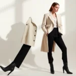 A deconstructed oversized blazer in cream with dramatic asymmetrical panels and unexpected geometric cutouts, worn with minimalist black trousers and sculptural black boots, captured against a neutral studio backdrop with dramatic side lighting.