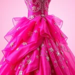 Close-up of an elaborate hot pink ball gown with intricate sequin embellishments and flowing layers, photographed on a dress form against a soft gradient background, studio lighting highlighting the fabric texture and sparkle