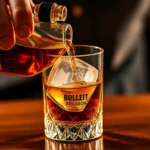 Close-up of hands expertly pouring amber Bulleit bourbon into a crystal rocks glass with large ice cube, warm golden lighting highlighting the bourbon's rich color and viscosity