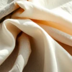 Sustainable fashion materials display: organic cotton, recycled polyester, and innovative eco-friendly fabrics arranged artfully with natural lighting, close-up product photography showcasing texture and quality, photorealistic detail