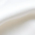 Close-up of premium cotton t-shirt fabric texture showing weave detail and quality, soft natural lighting highlighting fabric weight and drape characteristics