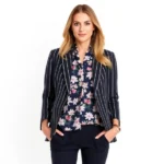 Professional fashion model wearing a navy and white striped blazer layered over a small-scale floral blouse, styled with neutral accessories and confident posture against clean white background