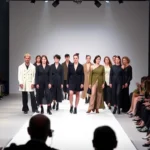 Diverse models wearing avant-garde designer clothing on a minimalist white runway, dramatic stage lighting, audience seated in foreground, contemporary fashion show atmosphere, professional photography