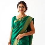 A woman in an elegant emerald green silk saree with gold temple jewelry, standing confidently against a minimalist white backdrop, natural lighting highlighting the fabric's sheen and embroidery details, professional fashion photography style
