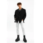 K-pop idol wearing oversized monochromatic black blazer with fitted white trousers, chunky platform boots, and statement silver chain necklace, standing against minimalist white background, fashion photography style