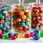 Close-up of vintage glass apothecary jars filled with jewel-toned hard candies in emerald, sapphire, and ruby hues arranged by color gradient on white marble surface with soft natural lighting