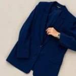 Overhead flat lay of oversized blazer with bold jewel tone fabric, chunky watch, and statement ring on neutral background, contemporary styling aesthetic, photorealistic