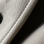 Close-up of premium fabric textures and refined seam construction on luxury fashion pieces, showing quality stitching details and sophisticated material composition