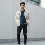 Asian male model wearing cream oversized button-up over navy fitted t-shirt, black slim jeans, white minimalist leather sneakers, standing against neutral urban background with natural lighting