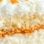 Close-up of fluffy coconut cake layer with golden crumb texture, fresh shredded coconut visible, professional bakery styling, natural lighting