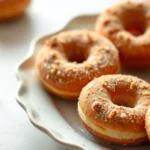 Golden-brown old fashioned doughnuts with crispy caramelized exterior dusted with cinnamon sugar, arranged on vintage ceramic plate with natural morning light, shallow depth of field, artisanal bakery aesthetic