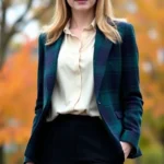 A woman wearing a tailored navy and forest green tartan blazer with cream silk blouse and black trousers, standing in natural light with autumn foliage background, professional polished styling