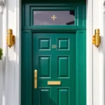 Luxury emerald green front door with brushed brass hardware and black marble surround, modern townhouse entrance, professional architectural photography, daylight